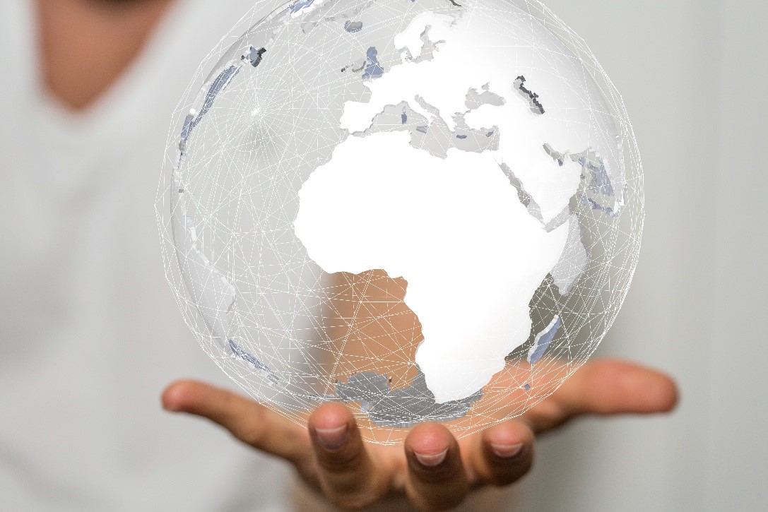 Mężczyzna trzyma w dłoniach przezroczystą kulę przedstawiającą mapę świata z siecią połączeń